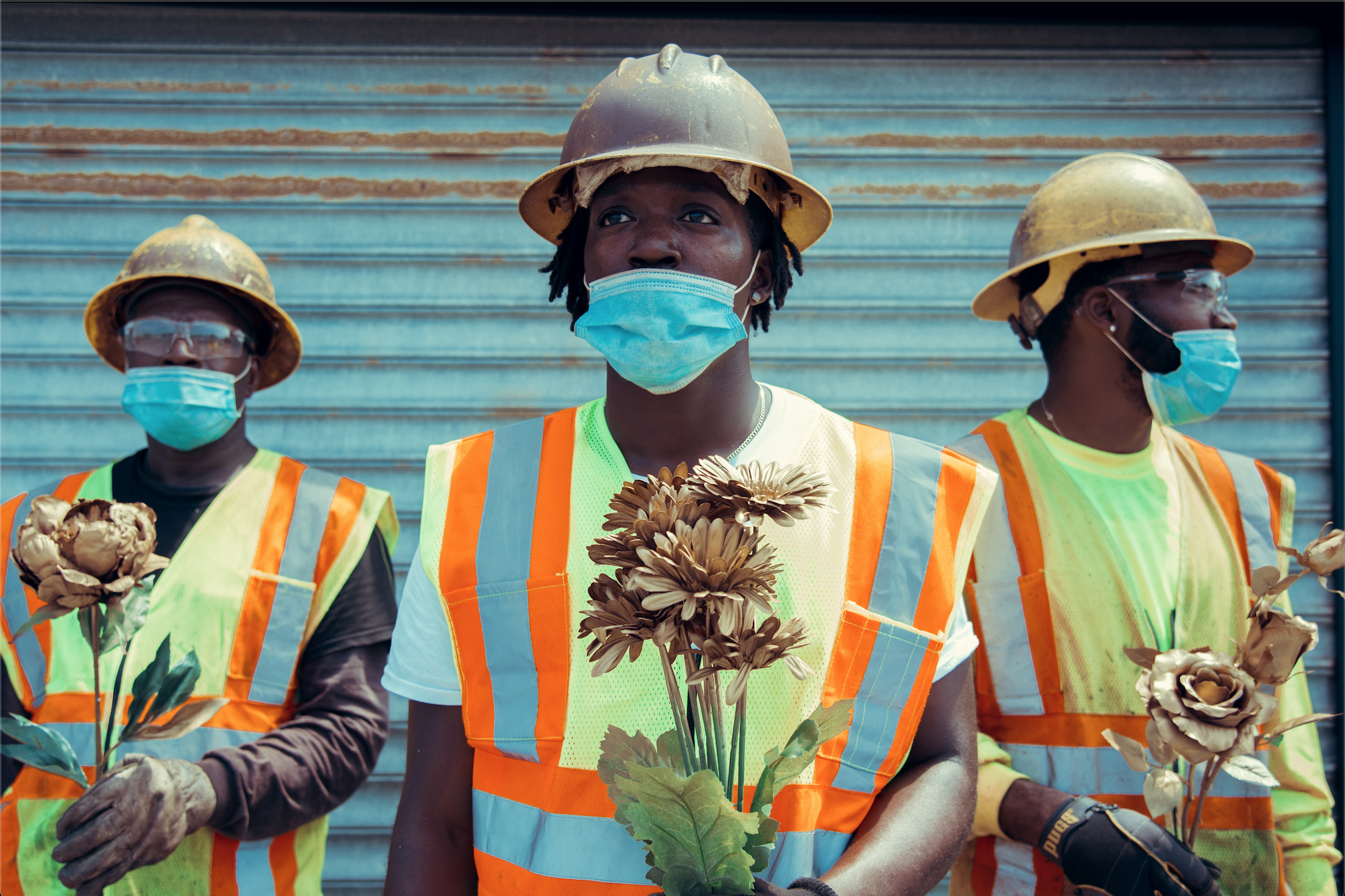 An image of three essential workers (construction) holding dried flowers taken by the artist who will be speaking