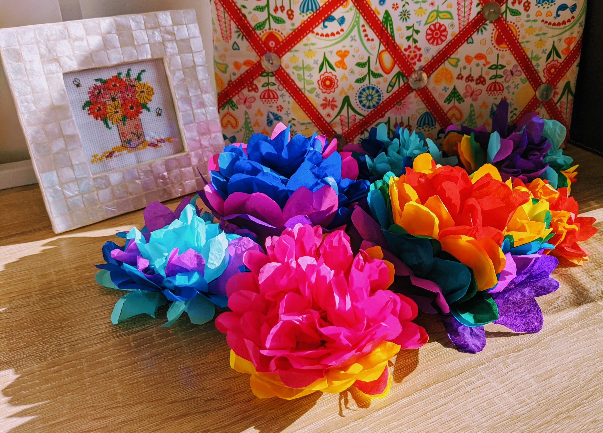 tissue paper flowers made from all different colors next to a framed picture
