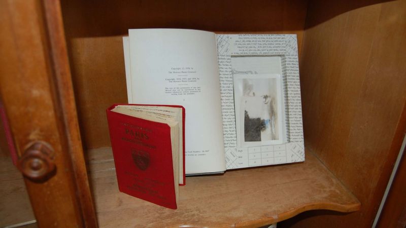 Red hardcover book with hole cut through the some of the pages with some keepsakes in the indentation.