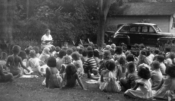 Librarian Mrs. Elinor H. Haff conducts an outdoor story time on the back lawn of the Sayville Library.