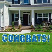Blue letters that spell Congrats! staked into a front yard