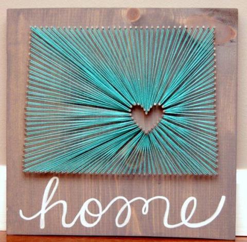wall hanging made of wood, with a heart made out of turquoise colored string that says 'home' in script under it