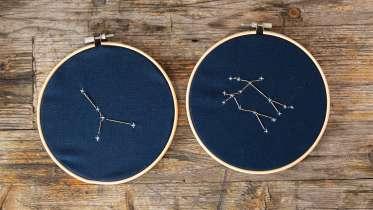 Two embroidery hoops featuring the embroidered constellations of Cancer and Gemini