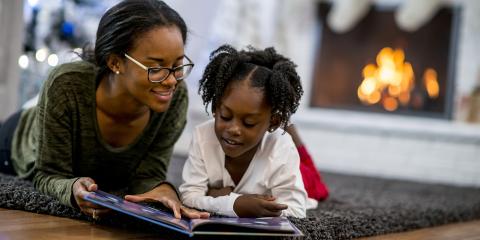 teen reading holiday book to child in front of fireplace