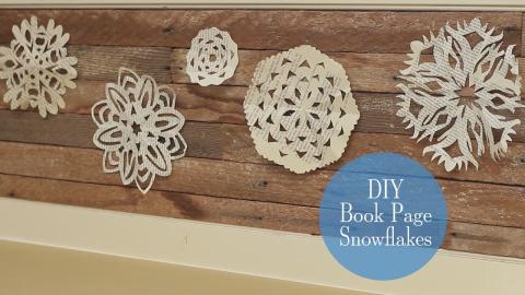 five snowflakes of different sizes cut from old book pages