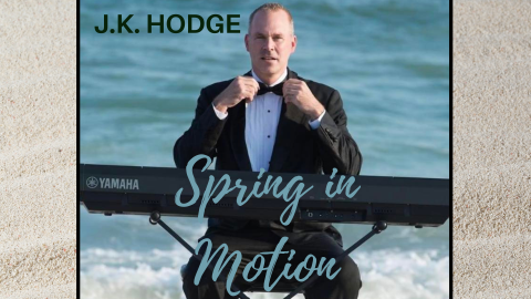 JK Hodge sitting at a keyboard on the beach.