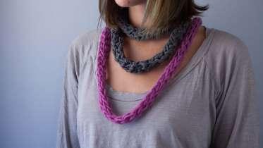 A woman wearing a two finger knit scarves.